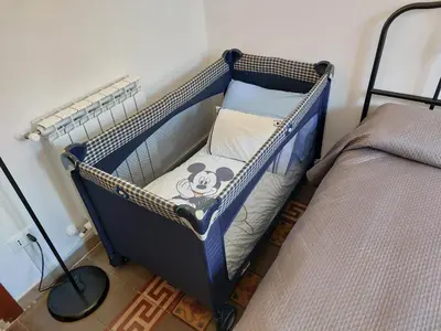 a baby crib with a mickey mouse pillow on it at Olivuzza Apartment in Palermo