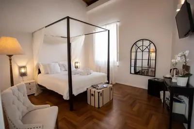 a bedroom with a canopy bed and a chair at Dimora Sinibaldi in Palermo