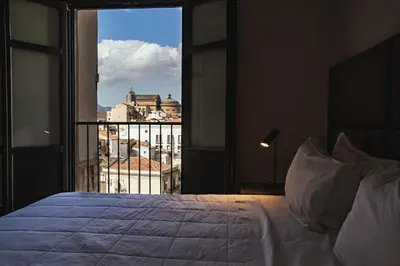 a building with tables and umbrellas in front of it at PALAZZO SANTAMARINA Luxury Suite & Spa in Palermo