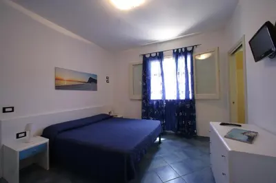 a bedroom with a blue bed and a television at Venere ed Enea - Appartamenti Vista Mare in San Vito lo Capo