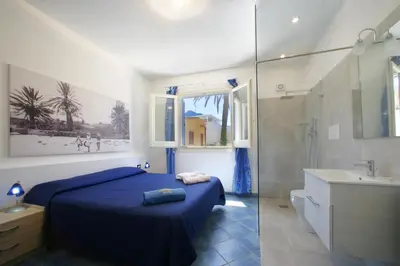 a bedroom with a blue bed and a shower at Venere ed Enea - Appartamenti Vista Mare in San Vito lo Capo