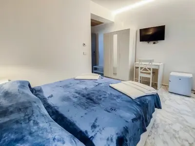 a blue bed in a white room with a television at Cubacalatafimi Rooms in Palermo