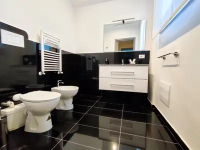 a black and white bathroom with a toilet and a sink at Cubacalatafimi Rooms in Palermo