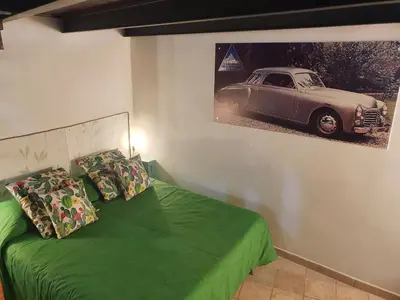 a bedroom with a green bed with a picture of a car on the wall at Casa Monviso Le fuoriserie in Palermo