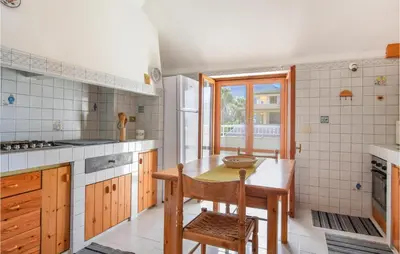 a kitchen with a wooden table and a wooden chair at Mansarda Belvedere in Alcamo Marina