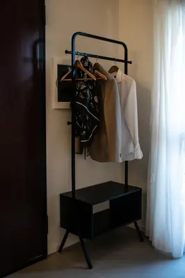 a black rack with clothes on it next to a window at Real suite spa in Palermo