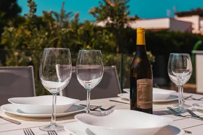 a table with a bottle of wine and three wine glasses at Gelso Bianco Boutique Apartments in Campofelice di Roccella