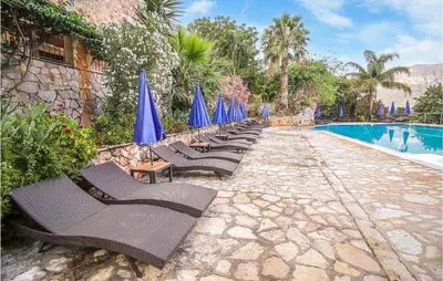 a row of chairs with blue umbrellas next to a swimming pool at Pietro 2 in San Vito lo Capo
