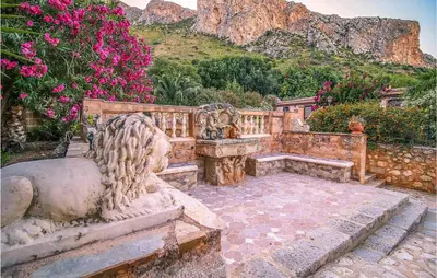 a stone bench in a garden with pink flowers at Pietro 2 in San Vito lo Capo