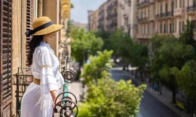 a woman in a hat standing on a balcony at A Casa di Anna - Apartment in Palermo