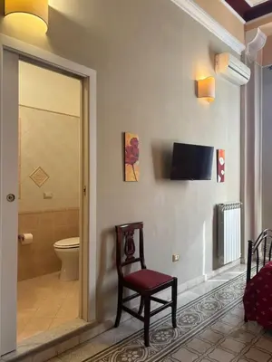 a bathroom with a toilet and a chair in a room at A Casa di Anna - Apartment in Palermo