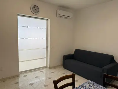 a living room with a couch and a clock on the wall at Oreto Apartment in Palermo