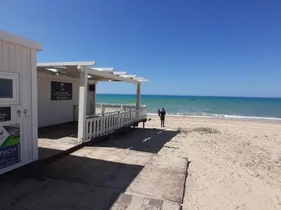 a person walking on the beach next to a building at Perla Home Speciale Vacanze 2026, Casa perfetta per gruppi coppie e famiglie vivi la Sicilia a modo tuo in Alcamo