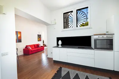 a white living room with a tv and a red couch at ChiChi Home in Palermo