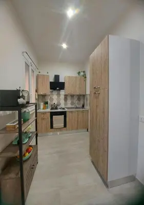 a large kitchen with wooden cabinets and a refrigerator at Le Due Pigne - Palermo in Palermo