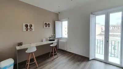 a kitchen with a counter and two stools in a room with windows at Garibaldi Rooms 29 - Piazza Marina a Palermo - In pieno Centro. in Palermo