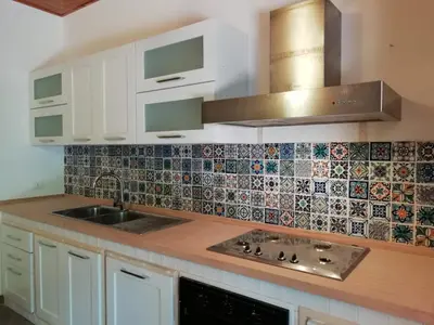 a kitchen with white cabinets and a sink and tiles at Villa Flora in Castellammare del Golfo