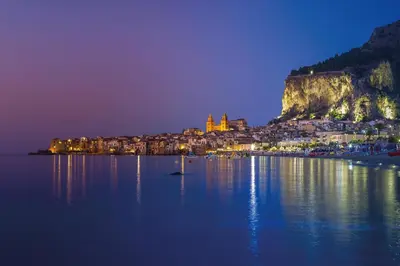 a view of a town at night with the water at Deluxe Sicily Villa in Buonfornello
