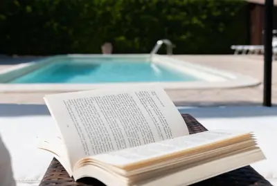 an open book sitting on a table next to a swimming pool at Deluxe Sicily Villa in Buonfornello