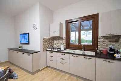 a kitchen with white cabinets and a sink and a window at Deluxe Sicily Villa in Buonfornello