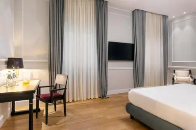 a hotel room with a bed and a desk and a bed and a desk at Grand Hotel Et Des Palmes in Palermo