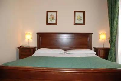 a bed with a wooden headboard and two lamps on tables at Hotel del Centro in Palermo