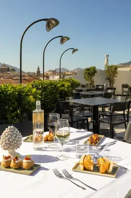 a table with plates of food and glasses of wine at Hotel Ambasciatori in Palermo