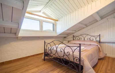 a bedroom with a bed in a attic with a window at Dimora Di Famiglia in Belmonte Mezzagno