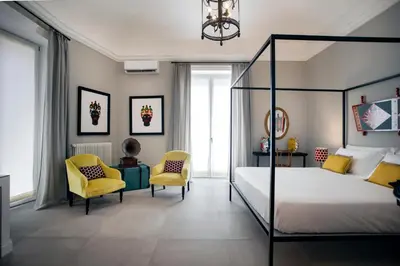 a bedroom with a bed and two chairs at Vossia Luxury Rooms & Sicilian Living in Palermo