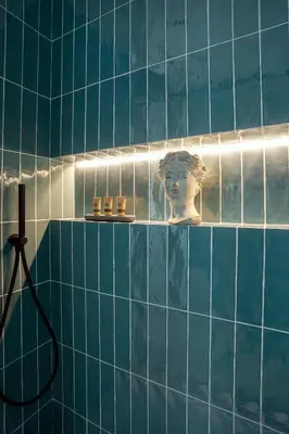 a blue tiled bathroom with a statue of a head on a shelf at Vossia Luxury Rooms & Sicilian Living in Palermo