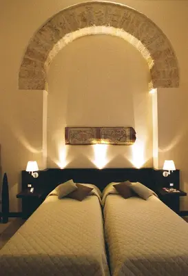 two beds in a room with an arch above them at Ucciardhome Hotel in Palermo