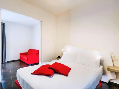 a white bed with a red chair in a room at President Hotel Palermo in Palermo
