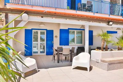 a patio with blue doors and a table and chairs at HolidaySicily Alcamo Marina in Alcamo Marina