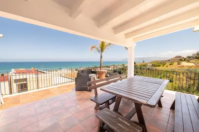 a patio with a table and a view of the ocean at HolidaySicily Alcamo Marina in Alcamo Marina