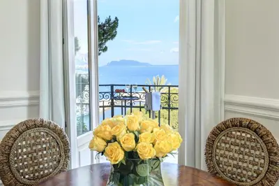 a vase of yellow roses sitting on a table with chairs at Rocco Forte Villa Igiea in Palermo