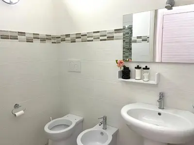a white bathroom with a sink and a toilet at Charmrooms in Castellammare del Golfo