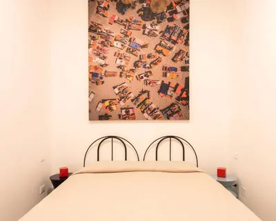 a bedroom with a bed with a painting on the wall at Sartoria Cavour - Modern Sicilian Elegance in a Former Tailor Shop in Palermo