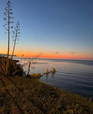 a sunset over the ocean with rocks in the water at Civic03 B&B in Terrasini