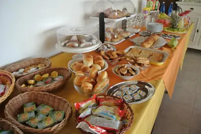 a table topped with baskets of bread and pastries at Hotel Il Melograno in San Vito lo Capo