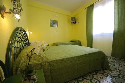 a bedroom with a bed in a yellow room at Hotel Il Melograno in San Vito lo Capo