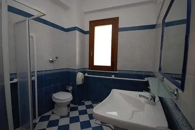 a blue and white bathroom with a toilet and a sink at Hotel Il Melograno in San Vito lo Capo