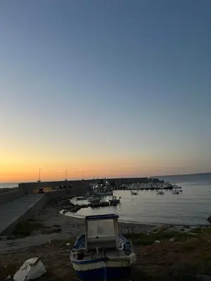 a boat sitting on the shore of a body of water at A-marè - CasaVacanza in Trappeto