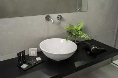 a bathroom with a white bowl sink on a black counter at Marmur Suite in Palermo