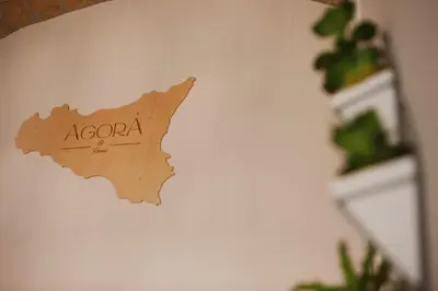 a wooden sign on a wall with a plant at Agorà Home in Terrasini