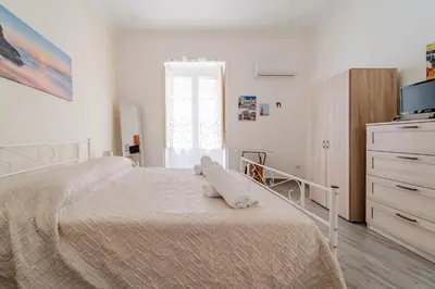 a white bedroom with a bed and a dresser at Casetta Holiday Meli in Palermo