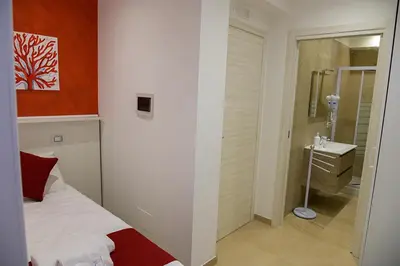 a bedroom with a bed and a bathroom with a sink at Corallo Rosso B&B in Terrasini