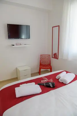 a bedroom with a bed with a red blanket and white towels at Corallo Rosso B&B in Terrasini