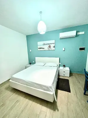 a bedroom with a white bed and a blue wall at B&B Santorini in Cinisi