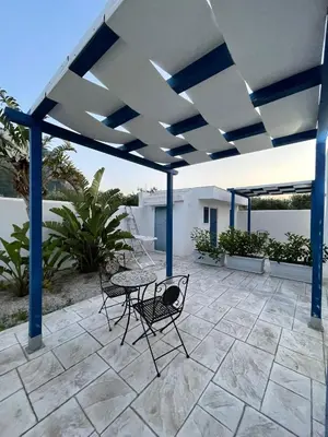 a patio with a table and chairs under a roof at B&B Santorini in Cinisi