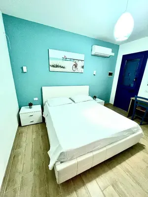 a bedroom with a white bed and a blue wall at B&B Santorini in Cinisi